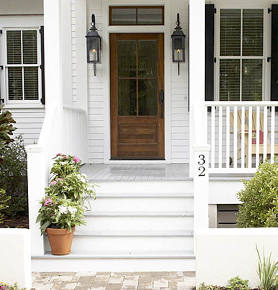 Simple two-story white house with wooden door, windows, and porch